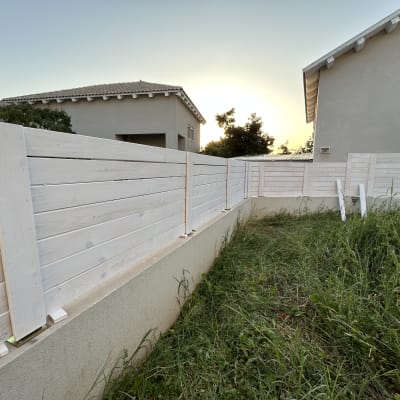 גדר עץ לבנה בחצר עם דשא ירוק