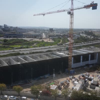 מנוף בנייה מעל אתר בנייה עם מבנה גדול