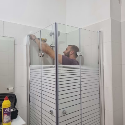 אדם מתקין דלתות זכוכית במקלחת