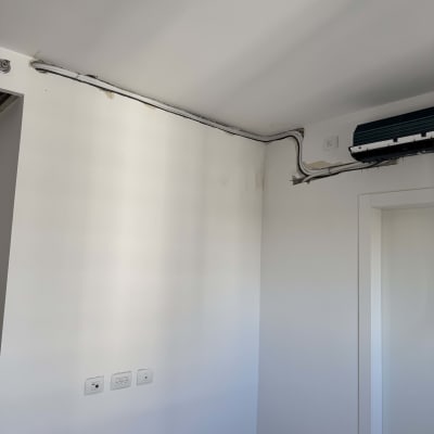 יחידת מיזוג אוויר מותקנת על קיר עם צינורות חשופים