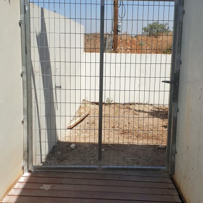 שער מתכת עם מסגרת רשת על רצפת עץ