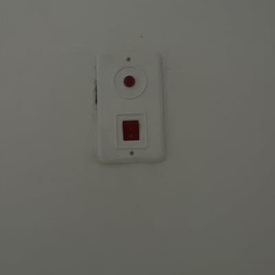 מתג חשמלי עם כפתור אדום על קיר