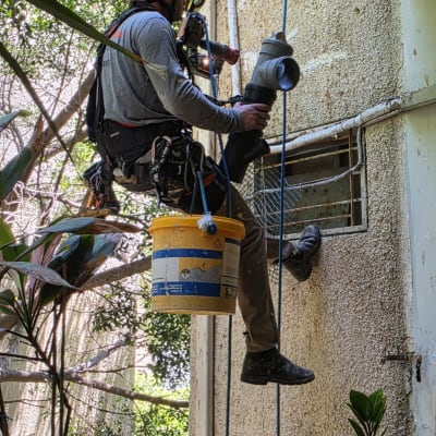 אדם בעבודת גובה על קיר בניין עם ציוד בטיחות