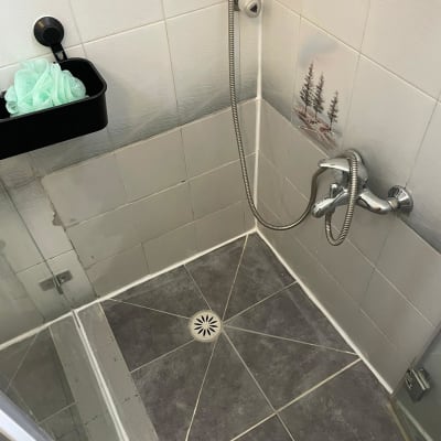 מקלחת עם אריחים אפורים וברז נירוסטה