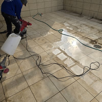 אדם מנקה רצפה עם מכונת שטיפה וחומר איטום