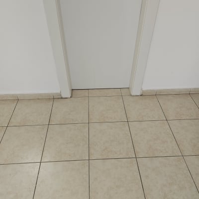 רצפת אריחים בהירה ודלת לבנה עם ידית מתכת