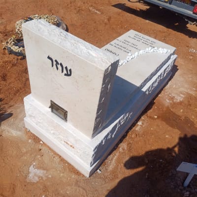 מצבה חדשה על אדמה עם רכב ברקע