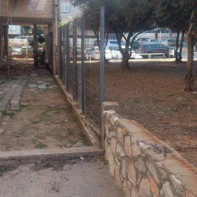 גדר מתכת ליד בניין ועצים