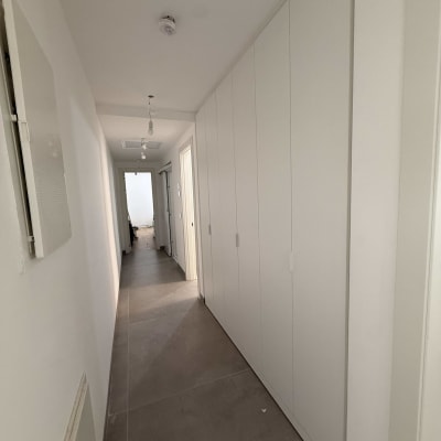 מסדרון עם ארונות קיר לבנים ותאורה עליונה