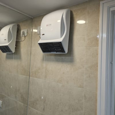 מייבש ידיים מותקן על קיר אריחים בחדר אמבטיה