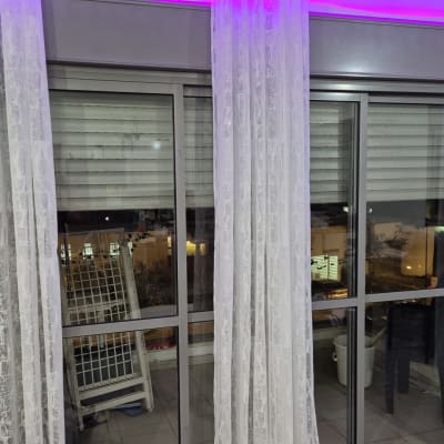 תריסים סגורים מאחורי חלונות זכוכית עם וילונות לבנים