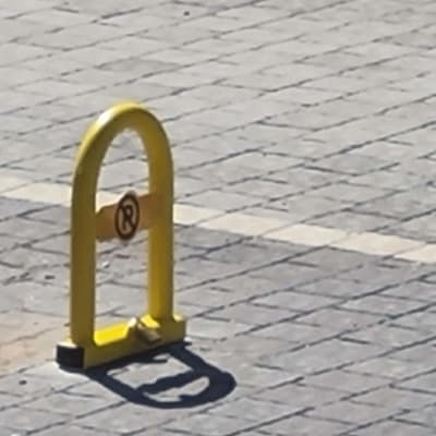 מחסום חניה צהוב על מדרכה מרוצפת