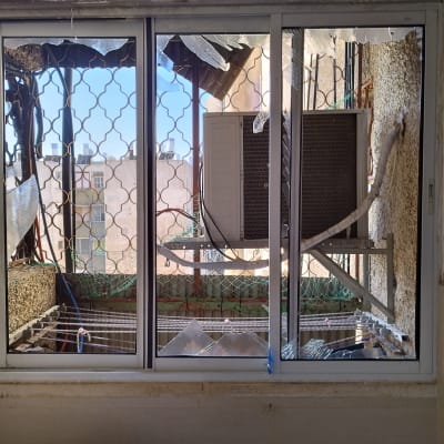 חלון עם תריסים שבורים ומסגרת מתכת