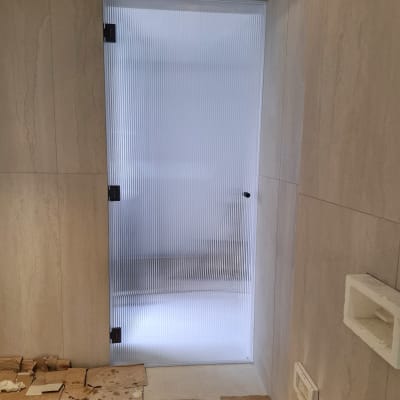 דלת זכוכית מחוספסת במקלחת עם קירות אבן