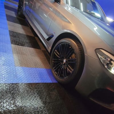 רכב כסוף עם גלגלים שחורים על רצפת מתכת רטובה