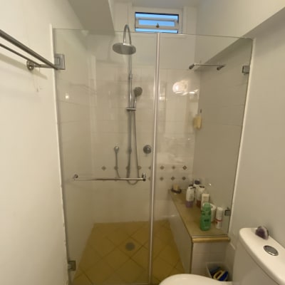 מקלחת עם דלת זכוכית ומוצרים על מדף