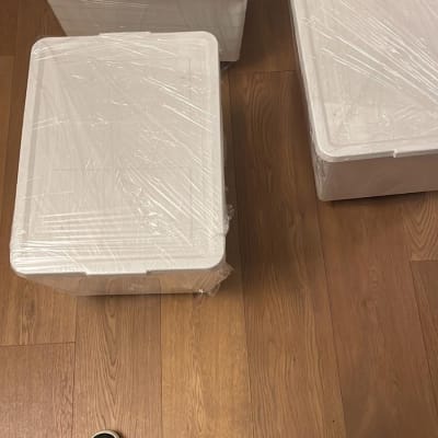 שלושה ארגזים לבנים עטופים בניילון על רצפה