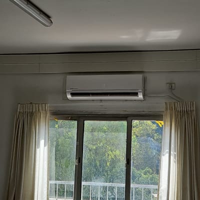 מזגן מותקן מעל חלון עם וילונות לבנים