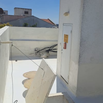 אדם על גג עם חומרי איטום וציוד עבודה