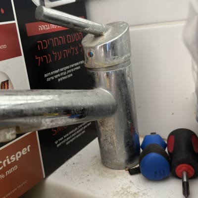 ברז מתכת עם מברגים על משטח לבן