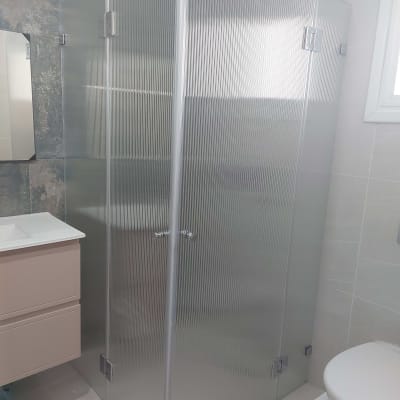 מקלחון זכוכית בחדר אמבטיה עם כיור ושירותים