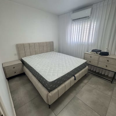 חדר שינה עם מיטה מרופדת ושידות תואמות