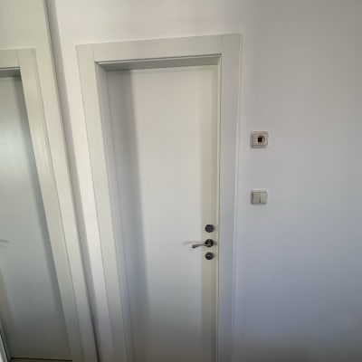 דלת לבנה עם ידית כסופה על קיר לבן