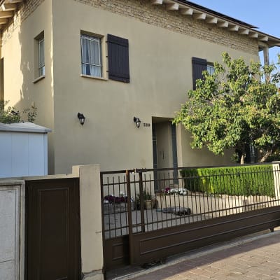 בית עם גדר חומה ועץ בחזית