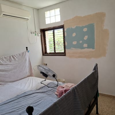 חדר עם מזגן, קיר בתיקון ומיטה