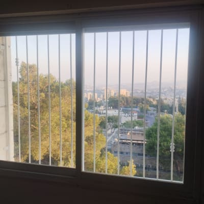 חלון עם סורגים נוף עירוני ועצים