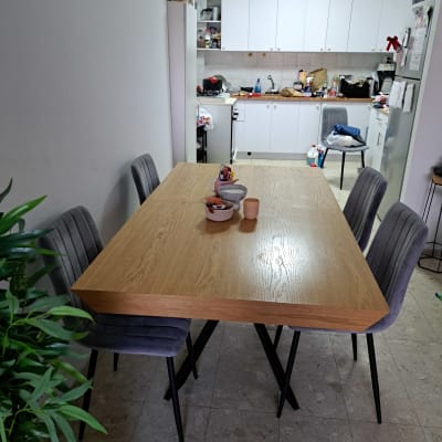 מטבח עם ארונות לבנים, שולחן עץ וכיסאות אפורים