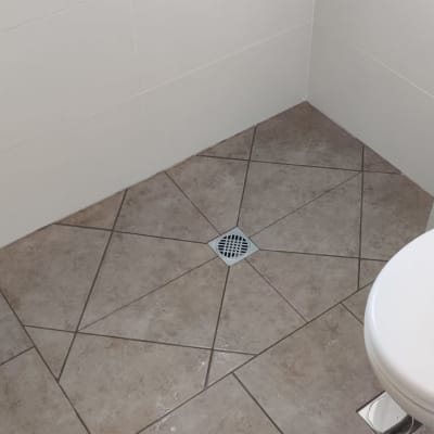 רצפת אריחים עם ניקוז ושירותים בחדר אמבטיה