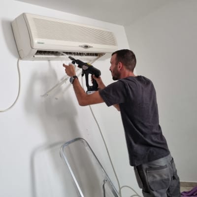 אדם מנקה מזגן עם מכשיר שטיפה בלחץ