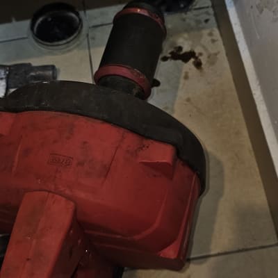 כלי עבודה אדום על רצפה ליד צינור ביוב