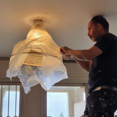 אדם מכסה מנורה בניילון להגנה מצבע