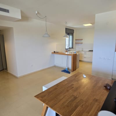 מטבח וחדר אוכל ריקים עם שולחן עץ ומנורות תלויות