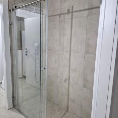 מקלחון זכוכית עם דלת הזזה וראש מקלחת