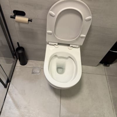 אסלה לבנה בחדר אמבטיה מודרני עם רצפת אריחים אפורה