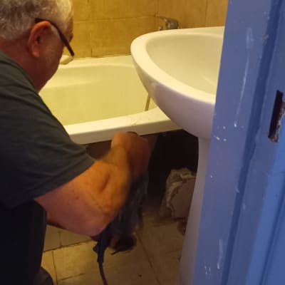 אדם עובד על צנרת ליד כיור ואמבטיה