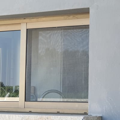 חלון זכוכית עם מסגרת מתכת על קיר בטון אפור