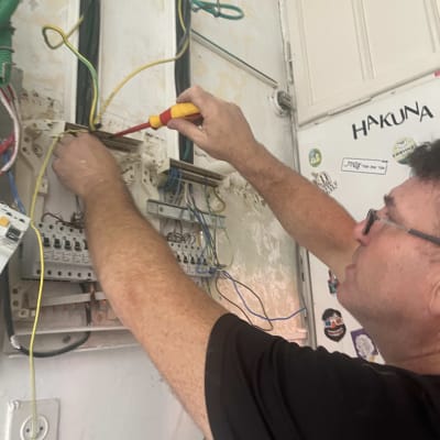 חשמלאי עובד על לוח חשמל עם מברג וחוטים