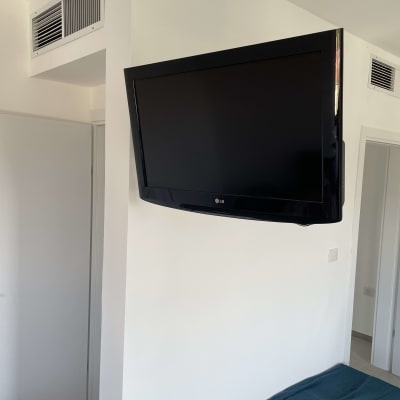 טלוויזיה מותקנת על קיר בחדר עם פתחי אוורור