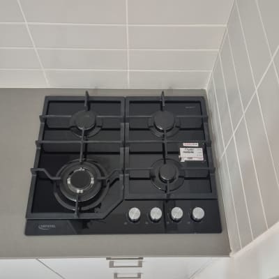 כיריים גז שחורות עם ארבעה מבערים וכפתורים כסופים