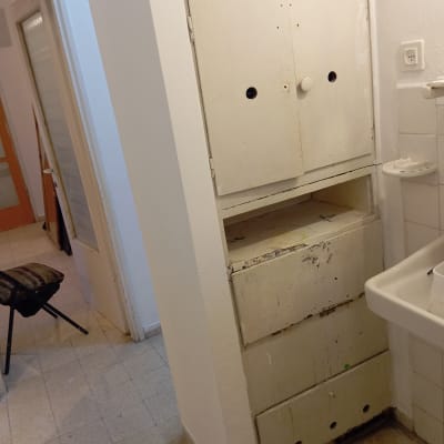 ארון ישן עם סימני צבע ליד כיור בחדר