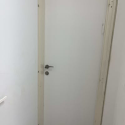 דלת לבנה עם ידית מתכת במסגרת עץ