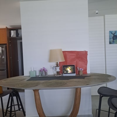 שולחן עם מנורה, מסך קטן, ופרחים על רקע קיר לבן