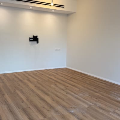 רצפת פרקט בחדר עם קיר לבן ותאורה