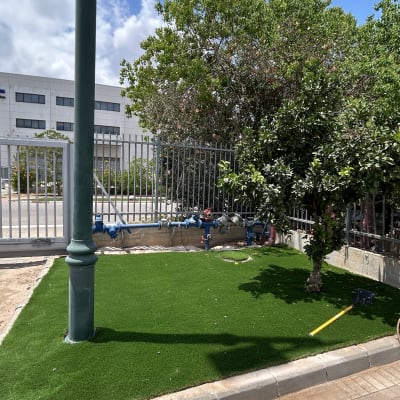 דשא סינתטי ליד עץ וגדר מתכת