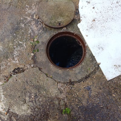 פתח ביוב פתוח עם מכסה מונח בצד