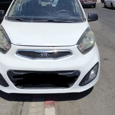 חזית רכב קיה לבן חונה על מדרכה